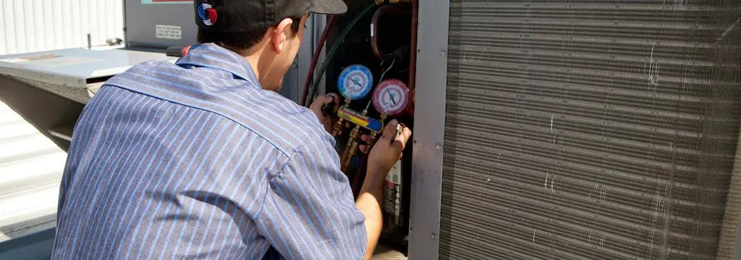 HVAC technician servicing a condenser unit in Hot Springs Village